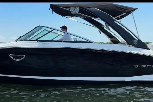 Slide: The Image of 2017 Regal 29 OBX boat with sleek black hull and canopy on the water. - 23