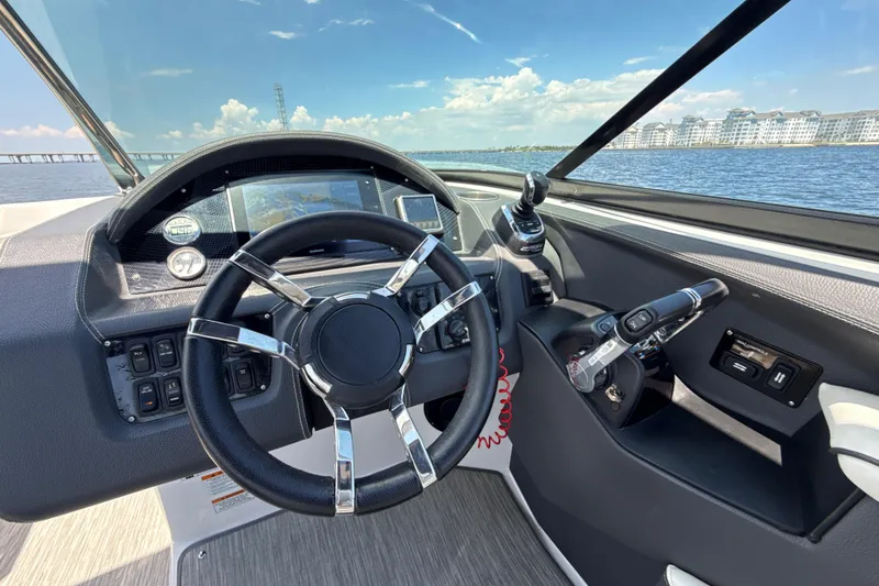 Slide: The Image of 2017 Regal 29 OBX boat dashboard with steering wheel and controls, overlooking water and buildings. - 25