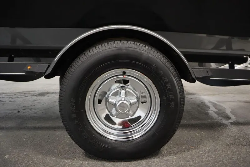 Slide: The Image of 2023 Tracker Pro Guide V-16 WT trailer wheel with chrome rim and black tire. - 56