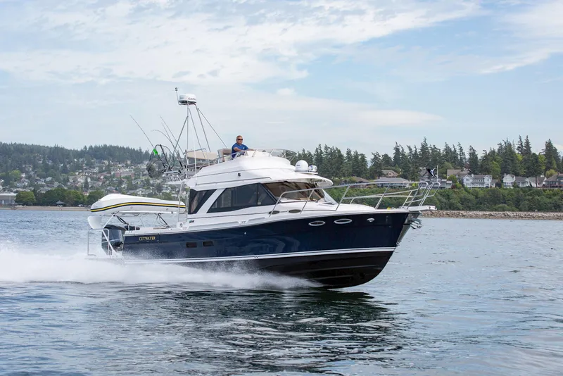 Slide: The Image of 2026 Cutwater C-32 CB cruising on a scenic waterway with coastal backdrop. - 11