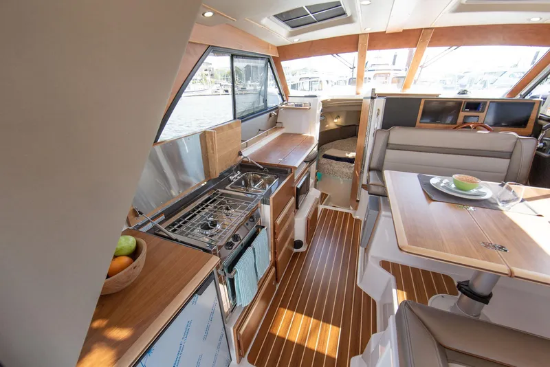 Slide: The Image of Interior of 2026 Cutwater C-32 CB yacht featuring kitchen and dining area with wood accents. - 4
