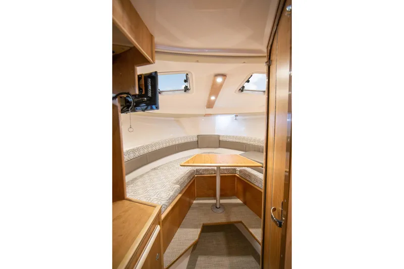 Slide: The Image of Interior of 2026 Cutwater C-288 C boat, featuring cozy seating and wooden table. - 11