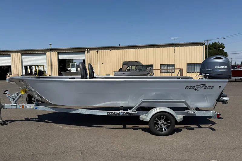 Slide: The Image of 2026 Fish Rite Angler 18 boat with Yamaha motor on trailer, parked outside a warehouse. - 1