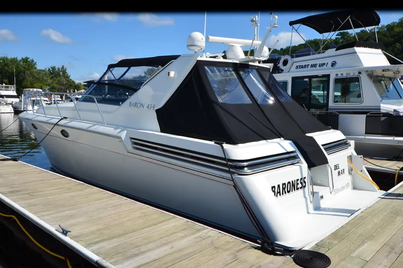 Slide: The Image of 1991 Baron 43-E yacht docked at marina, featuring sleek design and black canopy. - 41