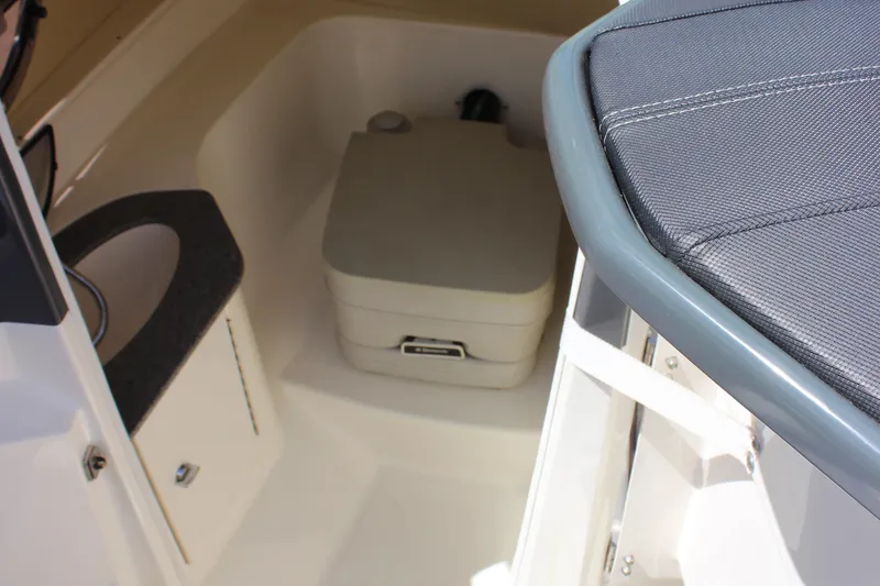 Slide: The Image of 2014 Larson LXi 258 IO boat interior with compact toilet and seating area. - 19