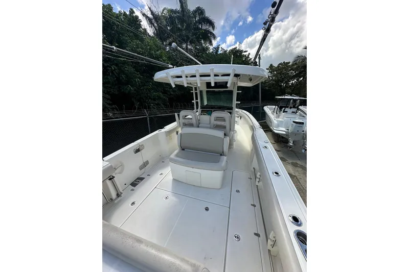 Slide: The Image of 2022 Boston Whaler 330 Outrage boat with spacious deck and seating, docked outdoors. - 11