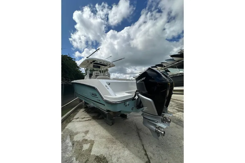 Slide: The Image of 2022 Boston Whaler 330 Outrage boat with Mercury outboard, docked under cloudy sky. - 14