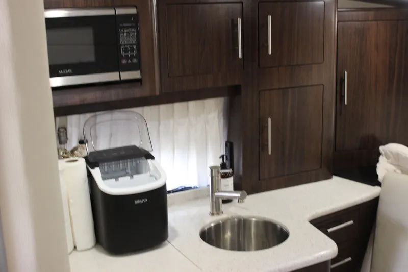 Slide: The Image of Compact kitchen area in a 2014 Regal 32 Express boat with microwave and sink. - 20