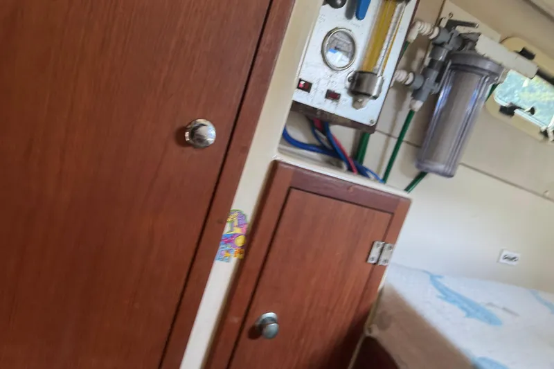 Slide: The Image of Interior of a 2008 Gemini 105Mc boat showing wooden cabinets and water filtration system. - 26