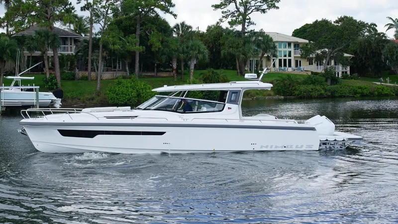 The Image of 2025 Nimbus Weekender 11 #60 cruising on a serene lake near luxury homes. - 0