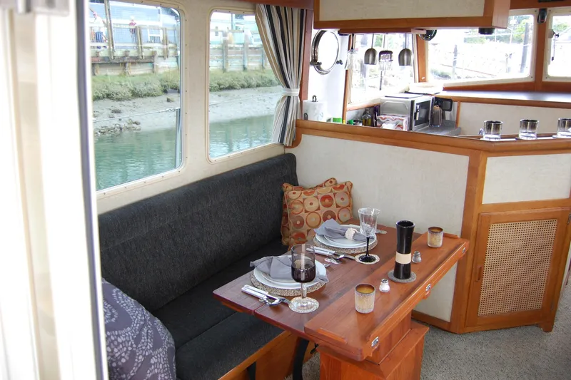 Slide: The Image of Cozy dining area inside a 1981 Willard Marine Pilot House Trawler, featuring elegant table settings. - 20