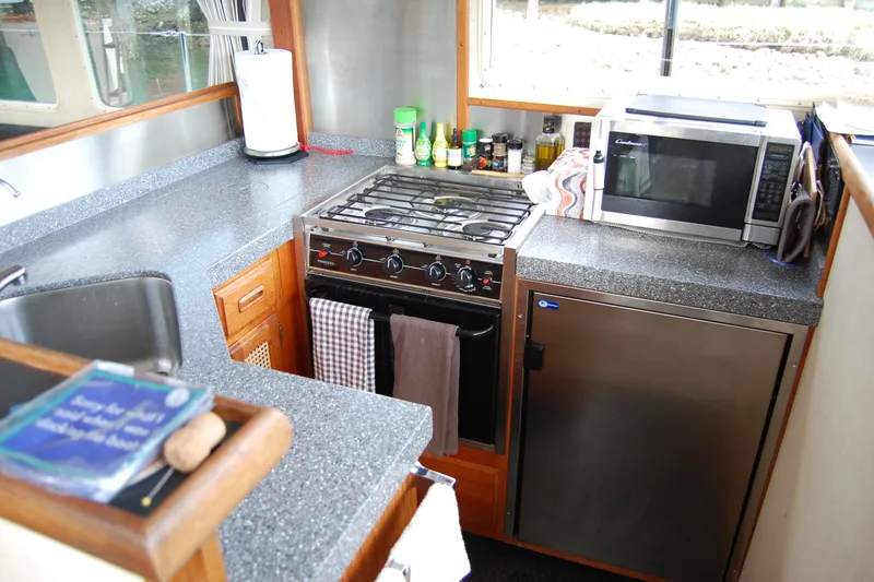 Slide: The Image of Compact kitchen in 1981 Willard Marine Pilot House Trawler with stove, microwave, and sink. - 25