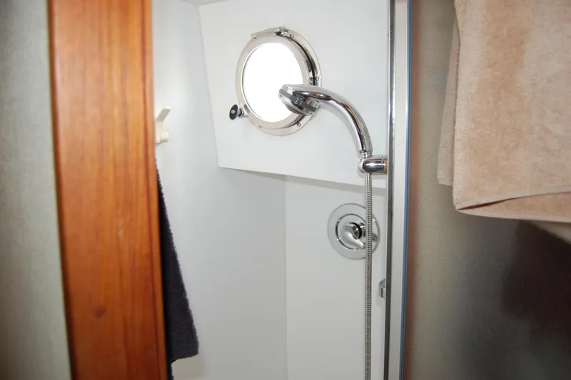 Slide: The Image of Shower area inside 1981 Willard Marine Pilot House Trawler, featuring a porthole and chrome fixtures. - 31