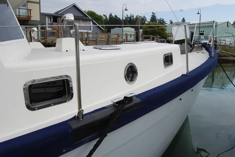 Slide: The Image of 1981 Willard Marine Pilot House Trawler docked, showcasing sleek white exterior and blue trim. - 5