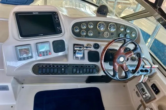 Slide: The Image of 2003 Cruisers Yachts 3772 Express helm with gauges, controls, and wooden steering wheel. - 13