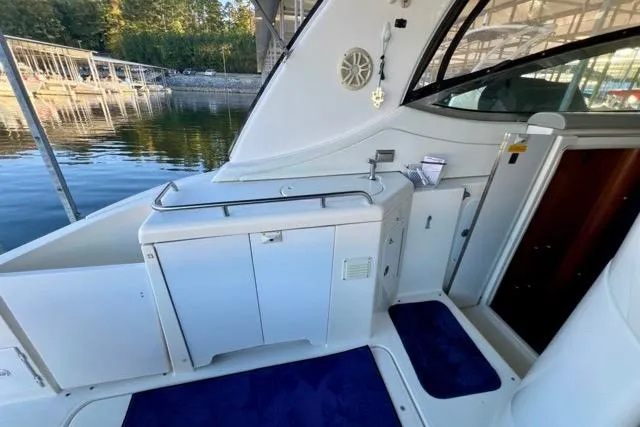 Slide: The Image of 2003 Cruisers Yachts 3772 Express interior with cabinets and blue carpet, docked by the water. - 15