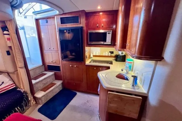 Slide: The Image of 2003 Cruisers Yachts 3772 Express interior with kitchenette, microwave, and wooden cabinetry. - 20