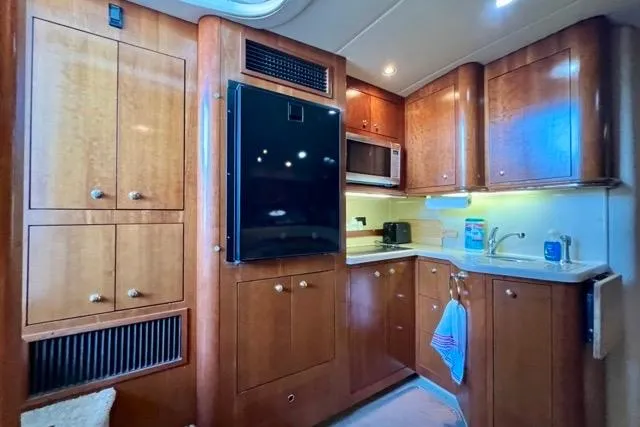 Slide: The Image of Luxurious 2003 Cruisers Yachts 3772 Express kitchen with wood cabinetry and modern appliances. - 21