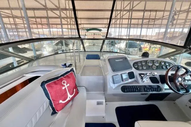Slide: The Image of 2003 Cruisers Yachts 3772 Express cockpit with steering wheel and anchor-themed pillow. - 11