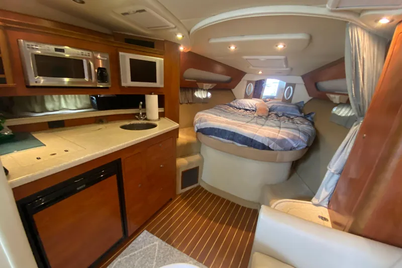 Slide: The Image of 2008 Rinker 350 Express Cruiser interior with kitchenette and cozy sleeping area. - 26
