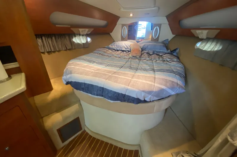 Slide: The Image of 2008 Rinker 350 Express Cruiser cabin with cozy bed and striped bedding. - 27