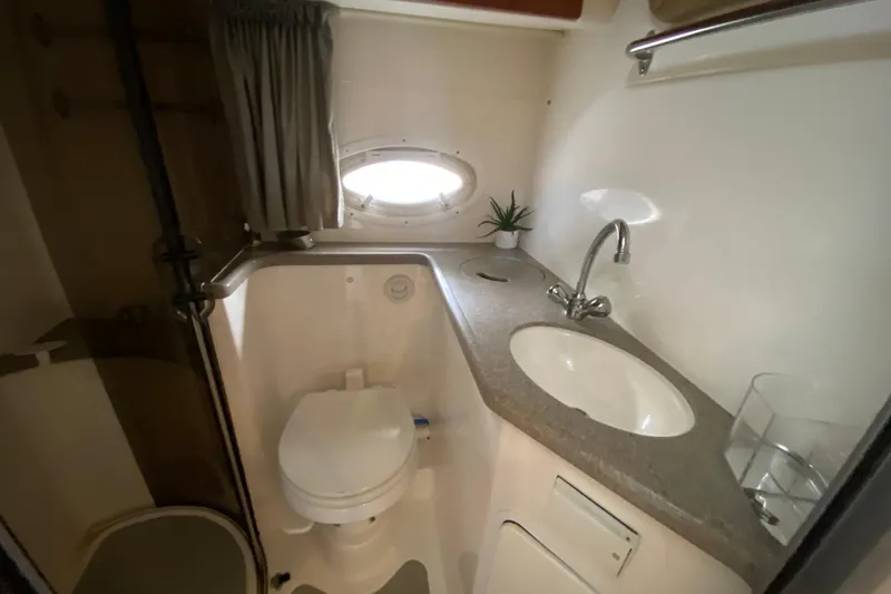 Slide: The Image of 2008 Rinker 350 Express Cruiser bathroom with sink, toilet, and porthole window. - 33