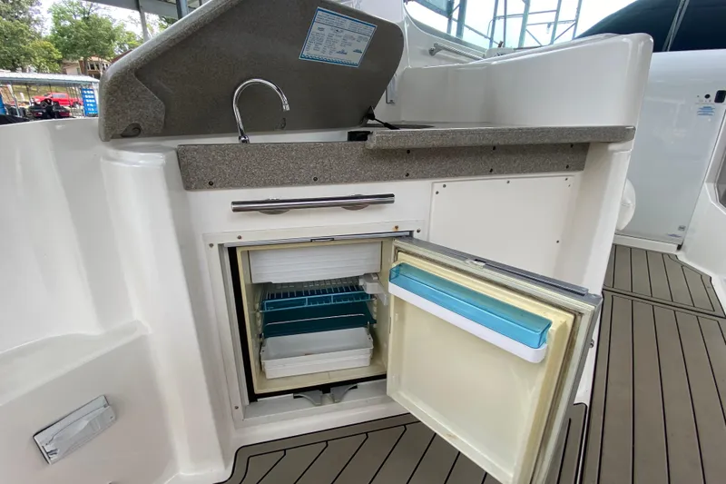 Slide: The Image of 2008 Rinker 350 Express Cruiser kitchenette with open mini fridge and sink. - 8