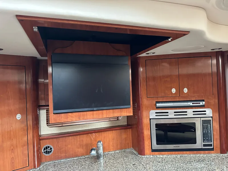 Slide: The Image of 2005 Sea Ray 420 Sundancer interior with TV, microwave, and wood cabinetry. - 44