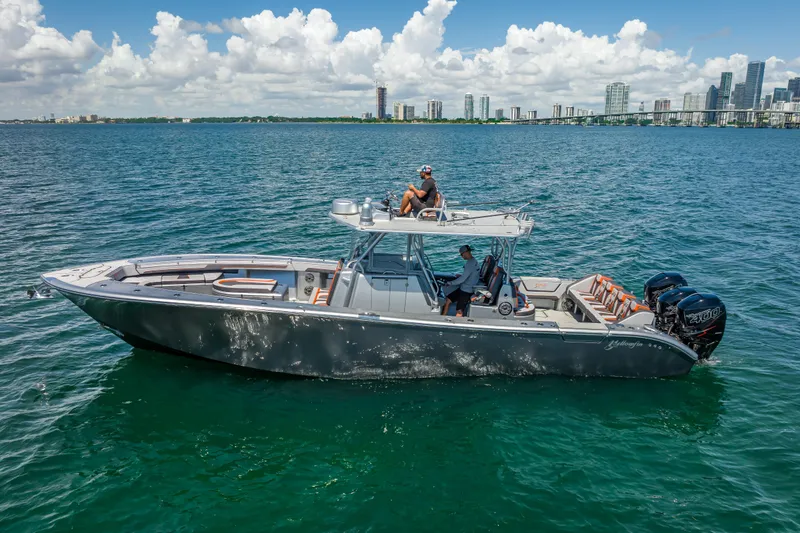 Slide: The Image of 2012 Yellowfin 39 boat cruising on water with city skyline in background. - 2