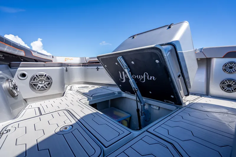 Slide: The Image of 2012 Yellowfin 39 boat interior with open storage hatch and speakers, under clear blue sky. - 56