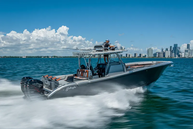 Slide: The Image of 2012 Yellowfin 39 boat speeding on water with city skyline in background. - 58