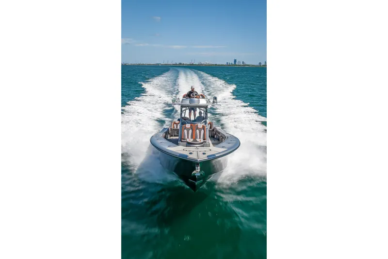 Slide: The Image of 2012 Yellowfin 39 boat cruising on open water with city skyline in background. - 86