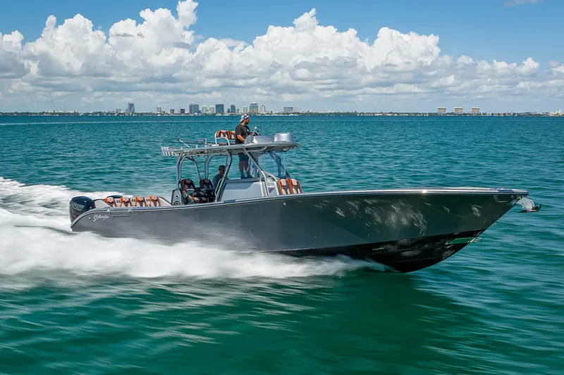 Slide: The Image of 2012 Yellowfin 39 boat cruising on open water with city skyline in background. - 87