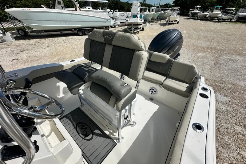 Slide: The Image of 2026 Key West 219 FS boat interior with seating and steering wheel, parked outdoors. - 15