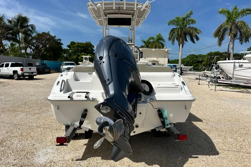 Slide: The Image of 2026 Key West 219 FS boat with outboard motor, parked on gravel lot with palm trees. - 4