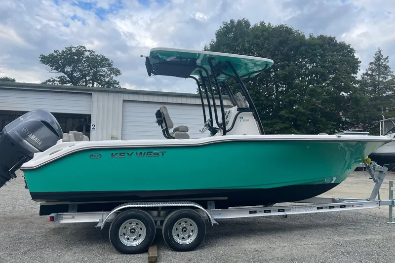Slide: The Image of 2024 Key West 239 FS boat on trailer, vibrant teal color, parked outdoors. - 7