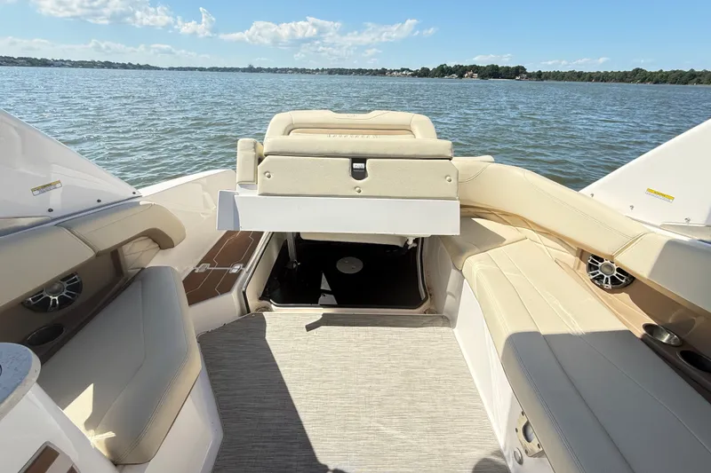 Slide: The Image of 2019 Regal 26 OBX boat interior with beige seating, on a calm lake. - 11