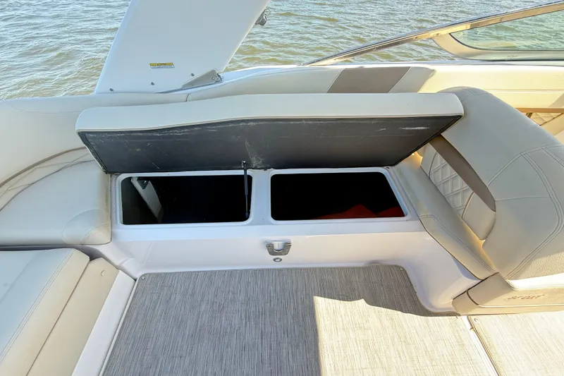 Slide: The Image of 2019 Regal 26 OBX boat interior with open storage compartment, beige seating, and water view. - 29