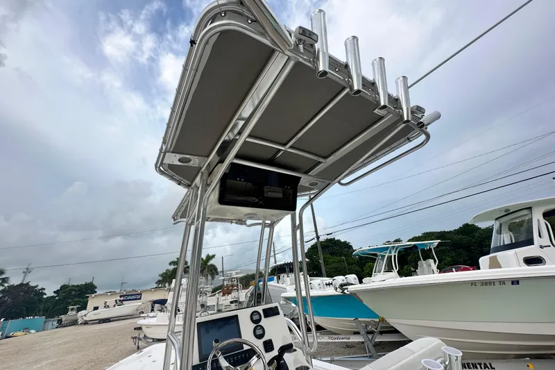 Slide: The Image of 2026 Key West 210 Bay Reef boat with T-top and rod holders, parked outdoors. - 13