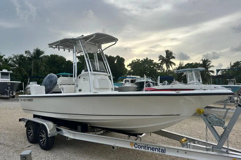 Slide: The Image of 2026 Key West 210 Bay Reef boat on trailer, parked outdoors with palm trees in background. - 6