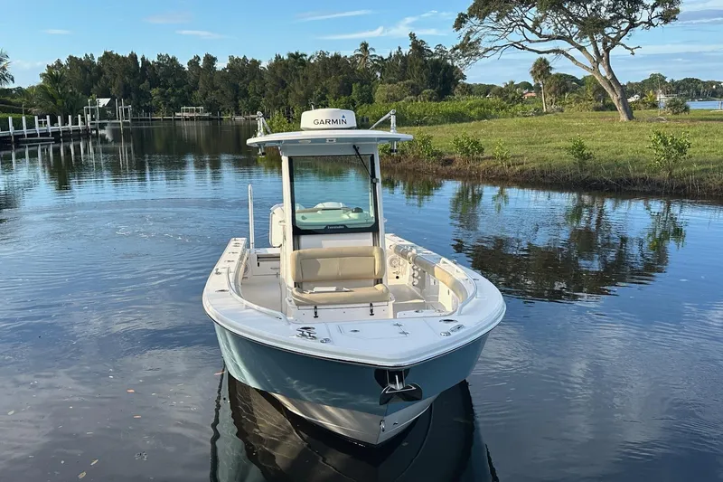 Slide: The Image of 2019 Everglades 273 Center Console boat on calm water, surrounded by lush greenery. - 2
