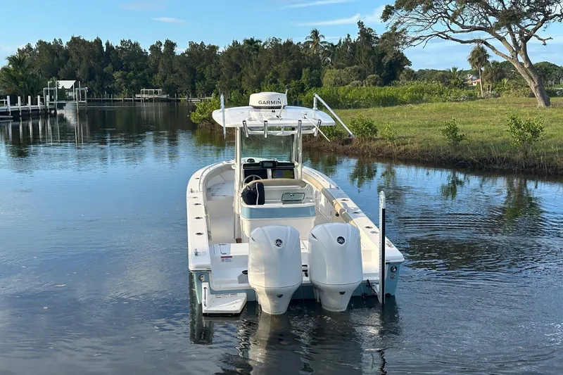 Slide: The Image of 2019 Everglades 273 Center Console boat on calm water, surrounded by lush greenery. - 3