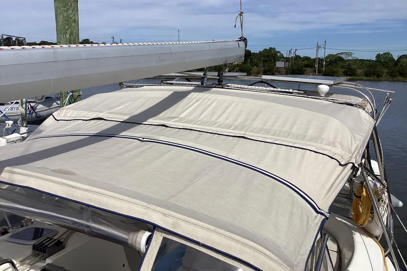 Slide: The Image of 2001 Hunter 380 sailboat with canvas cover docked by the water. - 10