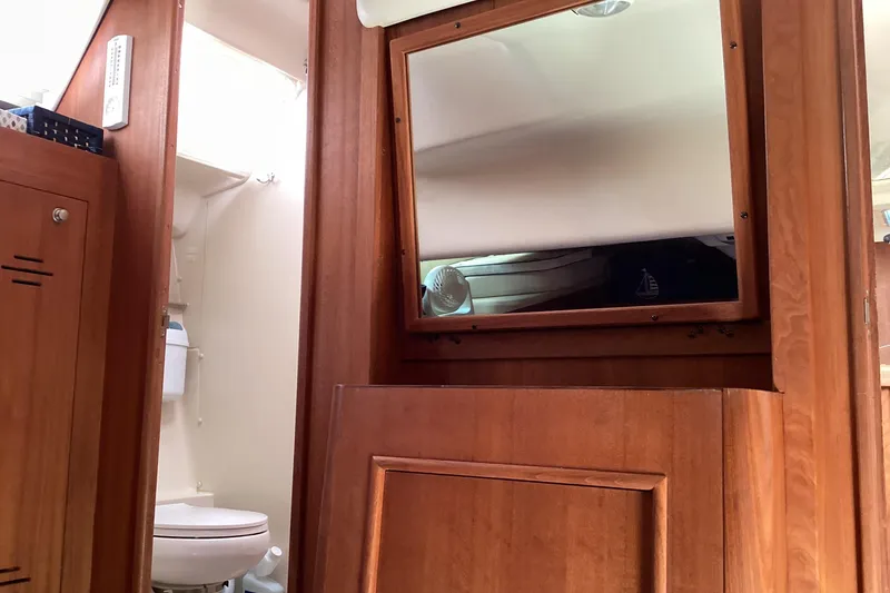 Slide: The Image of Interior of 2001 Hunter 380 sailboat showing wooden cabinetry and bathroom area. - 44