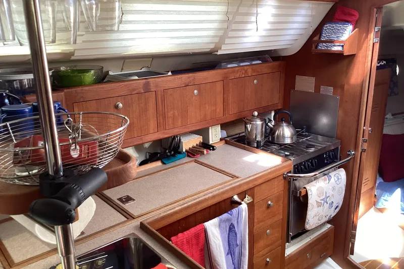 Slide: The Image of Compact kitchen in a 2001 Hunter 380 sailboat with wooden cabinets and stainless steel appliances. - 47