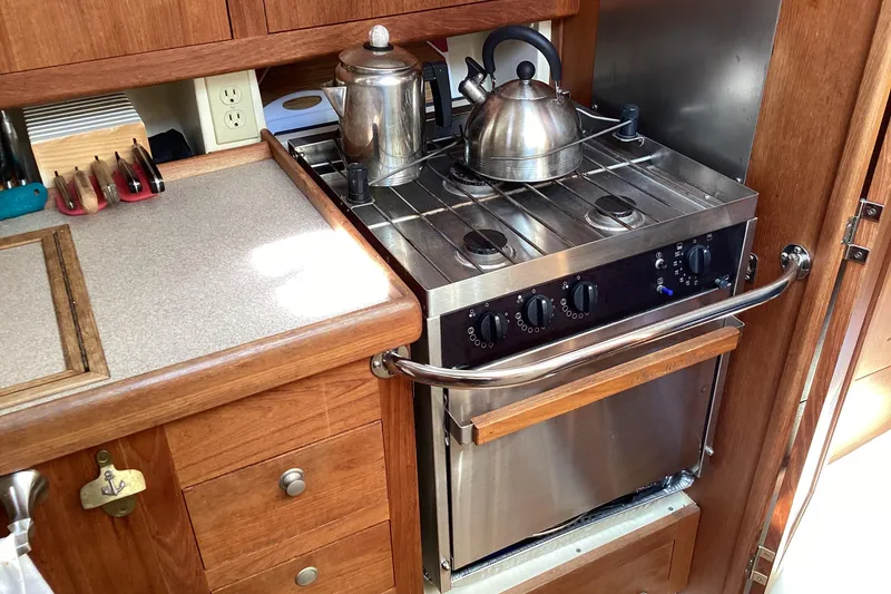 Slide: The Image of Compact kitchen in 2001 Hunter 380 sailboat with stove, kettle, and wooden cabinetry. - 48