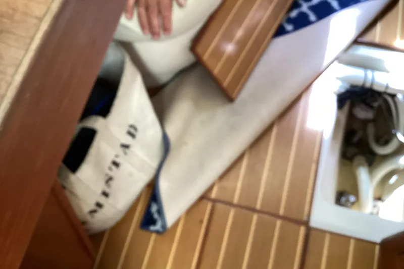 Slide: The Image of Interior of a 2001 Hunter 380 sailboat with wooden flooring and storage area. - 51