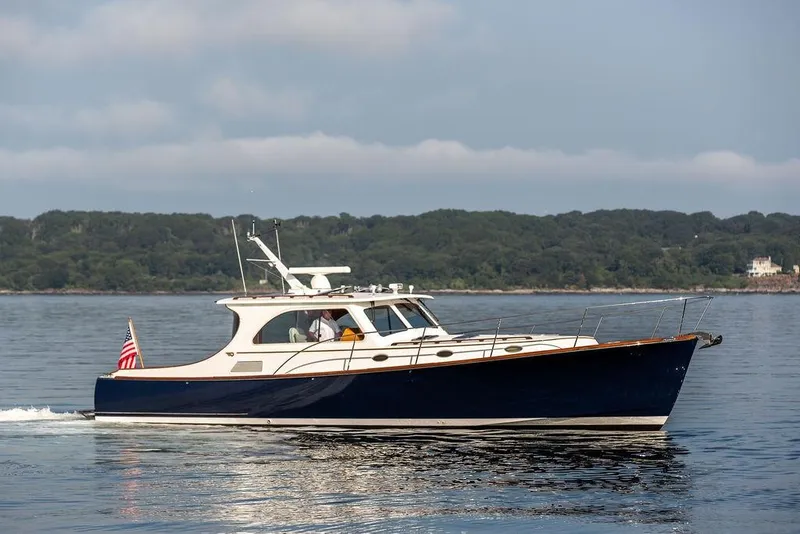 Slide: The Image of 2002 Hinckley Talaria 44 yacht cruising on calm waters with scenic shoreline backdrop. - 2