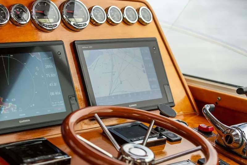 Slide: The Image of Hinckley Talaria 44 yacht dashboard with Garmin navigation screens and wooden steering wheel, 2002 model. - 23