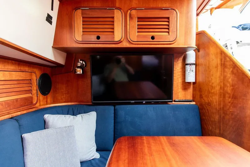 Slide: The Image of Interior of 2002 Hinckley Talaria 44 yacht with wood paneling, blue seating, and a mounted TV. - 26